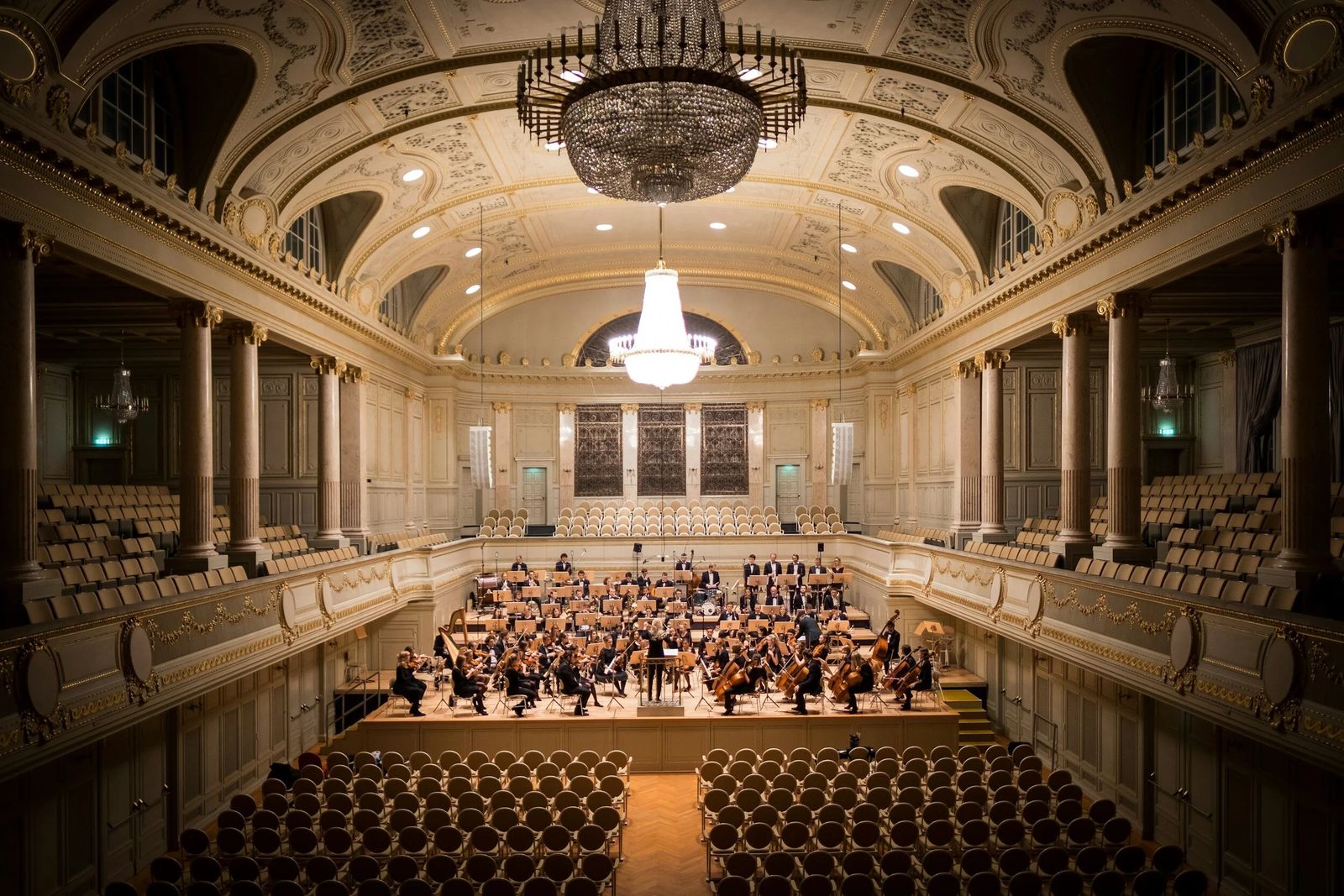 An orchestra performing in an ornate concert hall